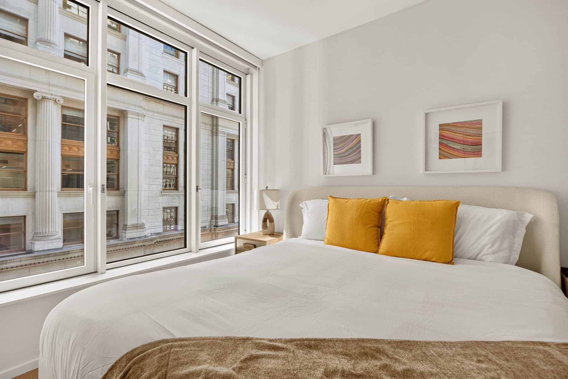 Bedroom with tall windows and mustard pillows