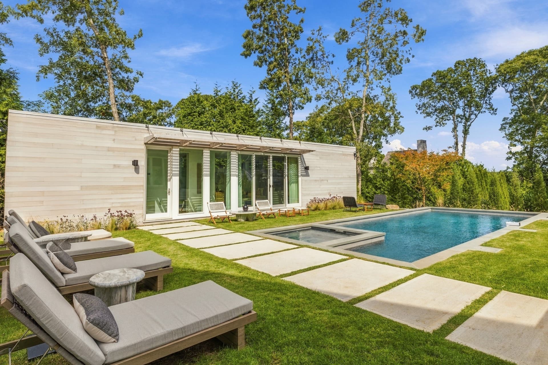 Low modern house with a lawn, pool and loungers