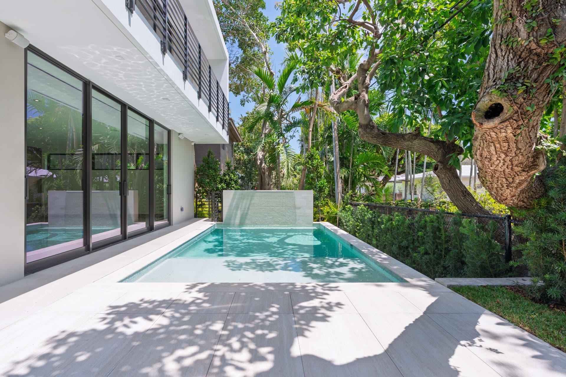 Narrow pool between a modern house and tropical garden