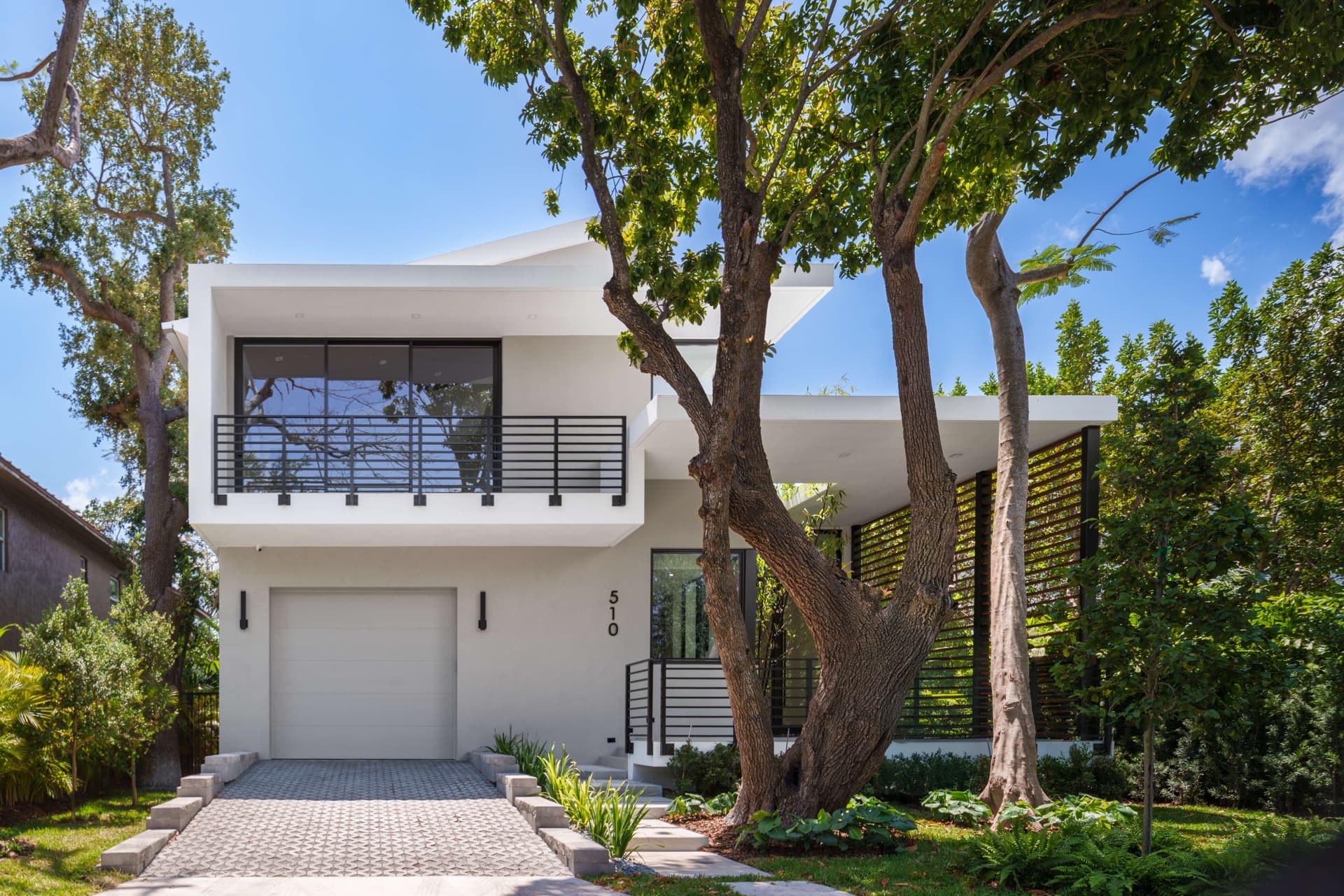 Modern white house behind tall trees