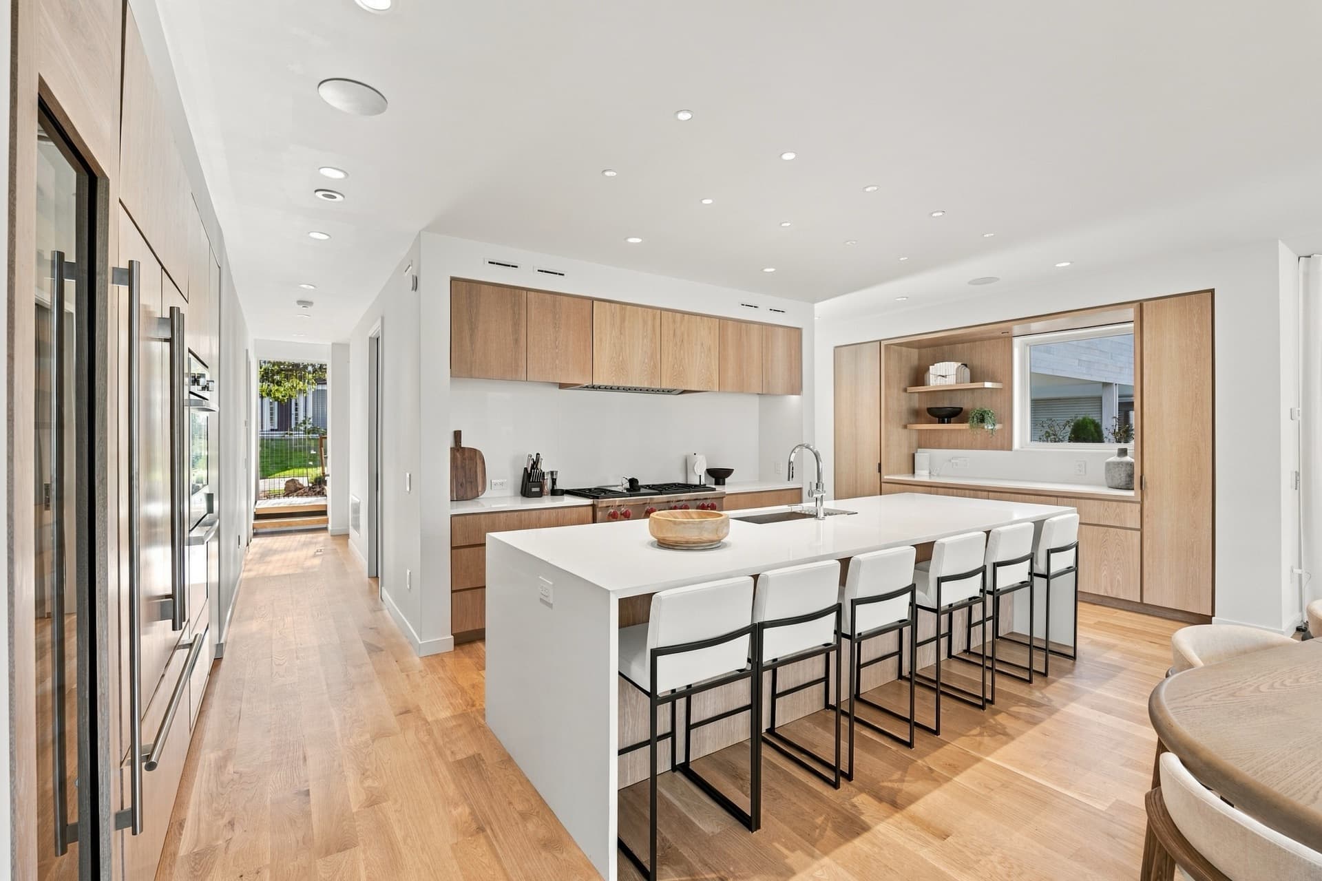 Kitchen with a clear white island and bar stools