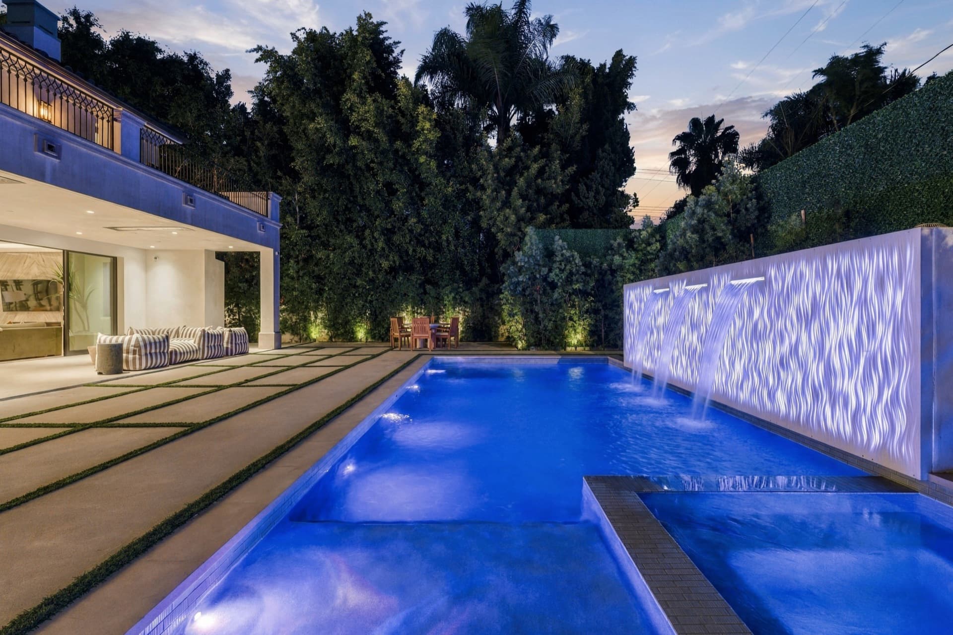Lit pool and water wall at dusk