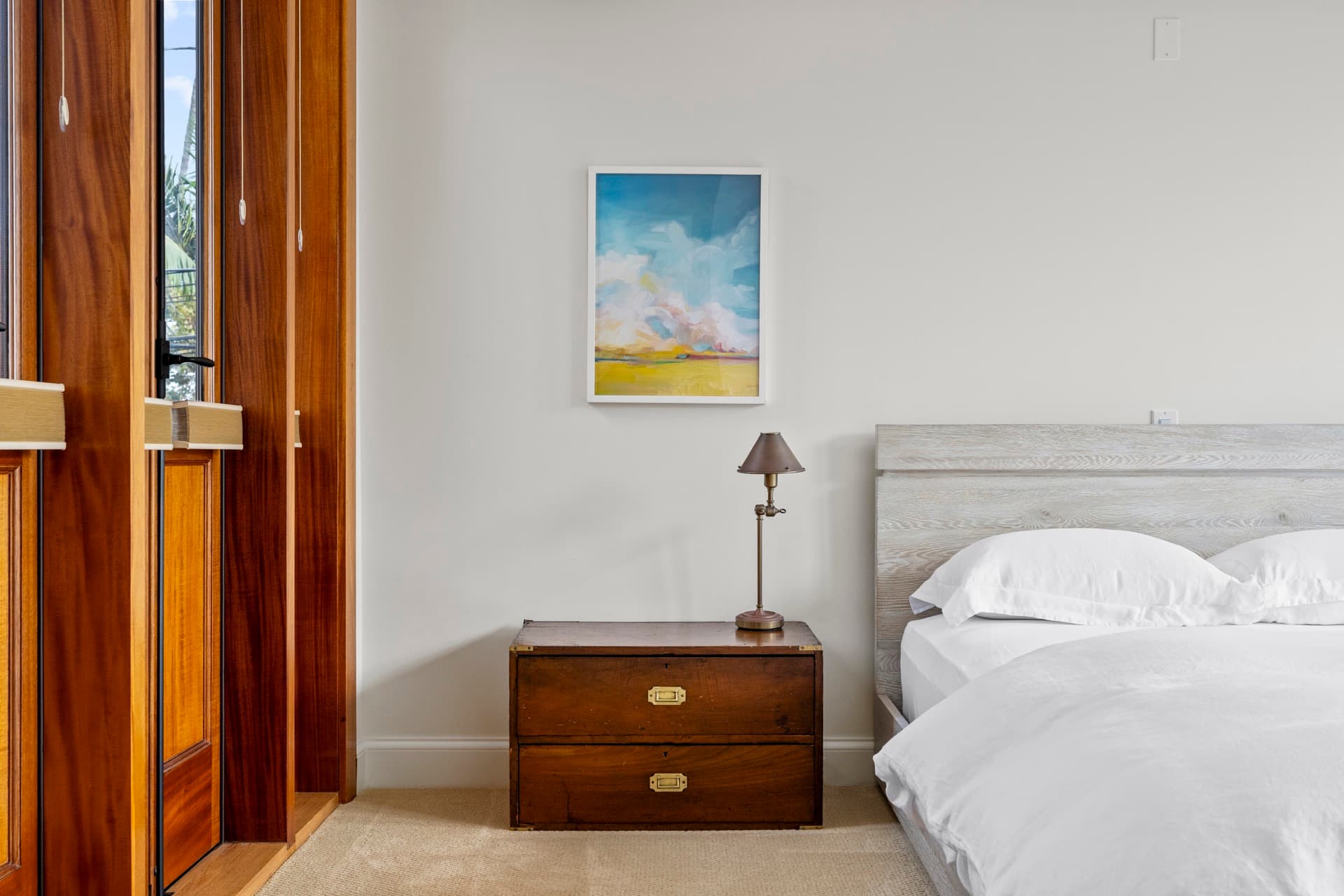Bedroom with a wood door, crisp white bedding and a lamp